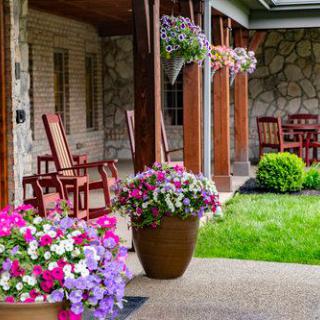 A cozy patio with wooden rocking chairs, vibrant flower pots, and lush garden landscaping.