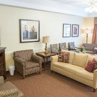 A cozy living room featuring a beige sofa, patterned armchairs, and warm decor.