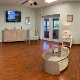A comfortable waiting room with a television, clock, and seating area on a wooden floor.