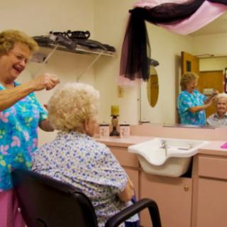 A hairdresser styles the hair of an elderly woman in a cozy salon.