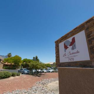 An outdoor view of a building with a sign and parking lot on a sunny day.