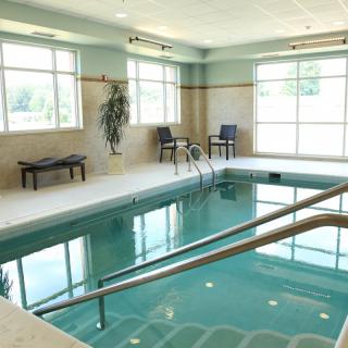 A serene indoor swimming pool surrounded by chairs and windows.