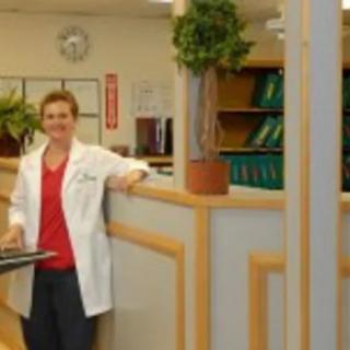 A medical professional stands in a hospital or clinic setting.