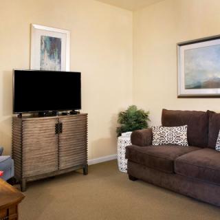 A cozy living room with a sofa, a television on a cabinet, and wall art.