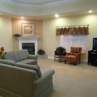 A cozy living room with a sofa, armchairs, fireplace, and television.