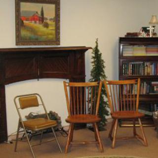 A cozy living room with wooden chairs, a bookshelf, and a decorative fireplace.