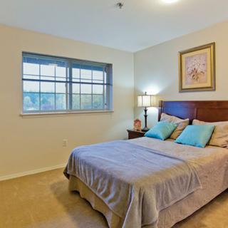 A cozy bedroom with a neatly made bed, soft lighting, and a window view.