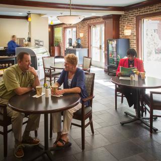 People in a cafe having conversations and using a laptop.