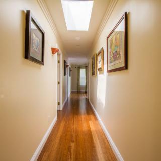 A well-lit hallway with wooden floors and artwork on the walls.