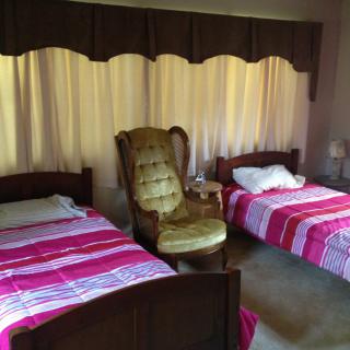 A cozy bedroom with twin beds and a comfortable armchair.