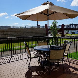 A sunny outdoor patio with a table, chairs, and an umbrella.