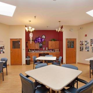 A communal space with tables and chairs, featuring a small kitchen area and decorative elements.
