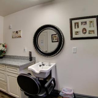 A modern hair salon setup with a circular mirror, sink, and decorative elements on the wall.