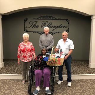A group of four individuals, including one in a wheelchair, pose together in a cheerful indoor setting.
