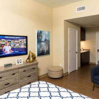 A cozy bedroom featuring a television, dresser, and elegant decor.