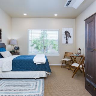 A modern bedroom with blue bedding, a window, and wall art.