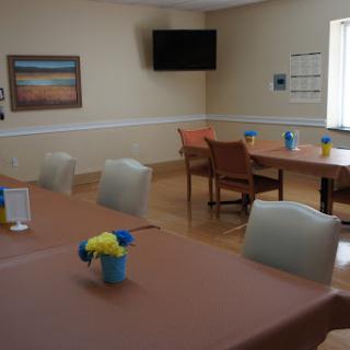 A spacious and inviting dining area featuring tables set for meals, decorative flowers, and a television.