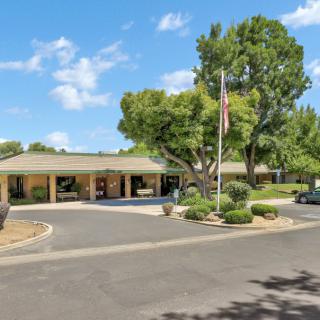 A suburban building with a landscaped driveway and flagpole, surrounded by trees.