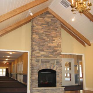 A spacious room with a stone fireplace, vaulted ceiling, and wooden beams.
