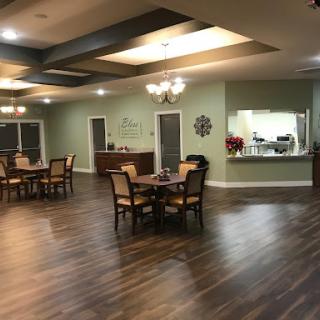 A spacious and inviting community dining area featuring wooden tables, comfortable chairs, and soft lighting.