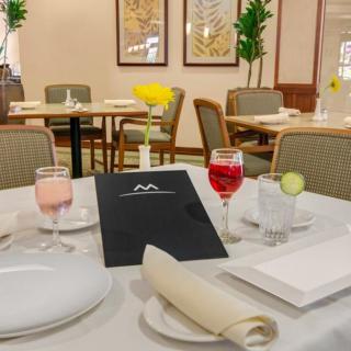 A neatly set table in a restaurant, featuring a menu and glasses with drinks.