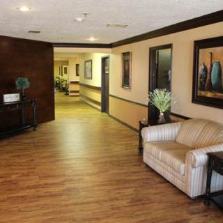 A spacious lobby with a sofa and decorative artwork, featuring warm wood flooring.