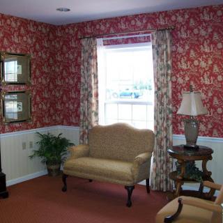 A cozy living room featuring floral wallpaper, a comfortable sofa, and elegant decor.