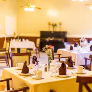 An elegant restaurant dining room with neatly set tables and floral centerpieces.