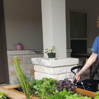 A person in a wheelchair tending to plants on a patio garden.
