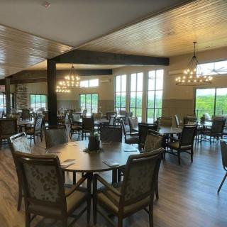 A spacious dining room with round tables and elegant chandeliers.