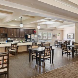 A spacious and modern dining area with tables and chairs, adjacent to a kitchen.