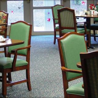 An indoor dining area with green upholstered chairs and wooden tables.