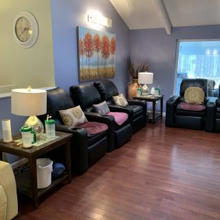 A cozy living room with comfortable recliners, warm lighting, and decorative wall art.