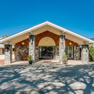 Front entrance of a building with stone columns and a peaked roof on a sunny day.