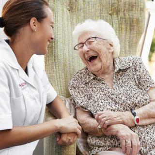 A caregiver and an elderly woman sharing a joyful moment together.