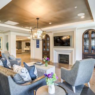 A stylish living room featuring a cozy seating area, modern fireplace, and elegant chandelier.