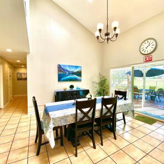 A bright dining room with a long table, chairs, chandelier, and a view of the patio.