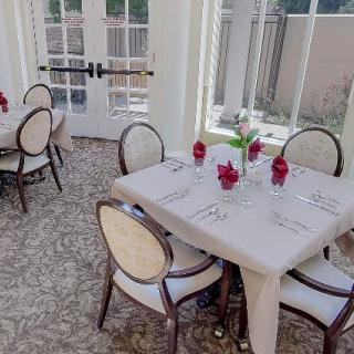 An elegant dining room with neatly set tables and chairs, featuring large windows providing a bright and inviting atmosphere.