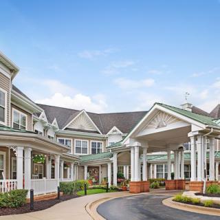 A picturesque view of a residential building with a covered entrance and well-maintained landscaping.