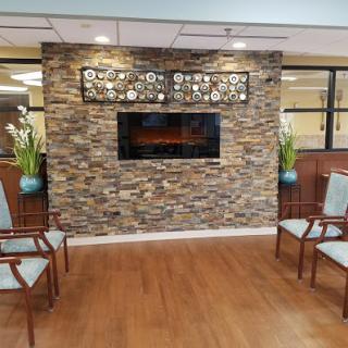 A cozy waiting area featuring a stylish stone wall with an electric fireplace and comfortable seating.