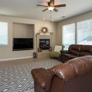 A cozy living room featuring leather sofas, a fireplace, and large windows.