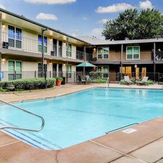 An outdoor swimming pool at an apartment complex on a sunny day.