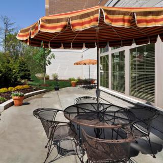 A cozy outdoor patio with chairs, a table, and umbrellas on a sunny day.