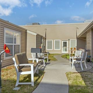 A courtyard with benches and a pathway in a residential area under a partly cloudy sky.