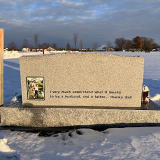 A serene winter setting featuring a memorial stone dedicated to a loved one.