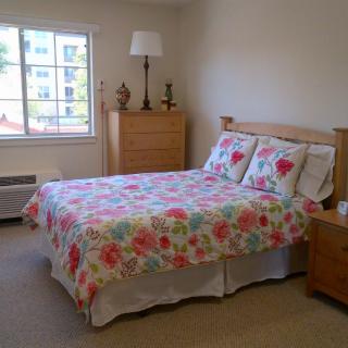 A cozy bedroom with a floral bedspread and wooden furniture.