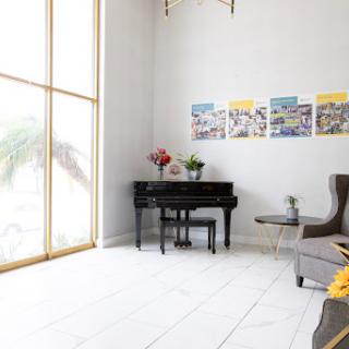 A bright and minimalist living room featuring a black piano and large windows that invite natural light.