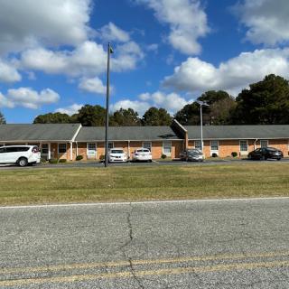 A roadside motel with cars parked in front under a blue sky with clouds.