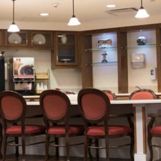 A cozy kitchen area with a row of red chairs at the counter, illuminated by warm overhead lights.