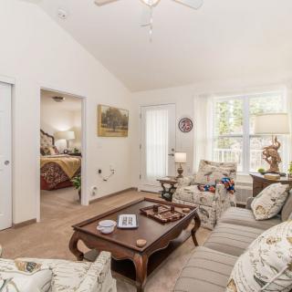 A bright and cozy living room with floral patterned furniture and wooden accents.